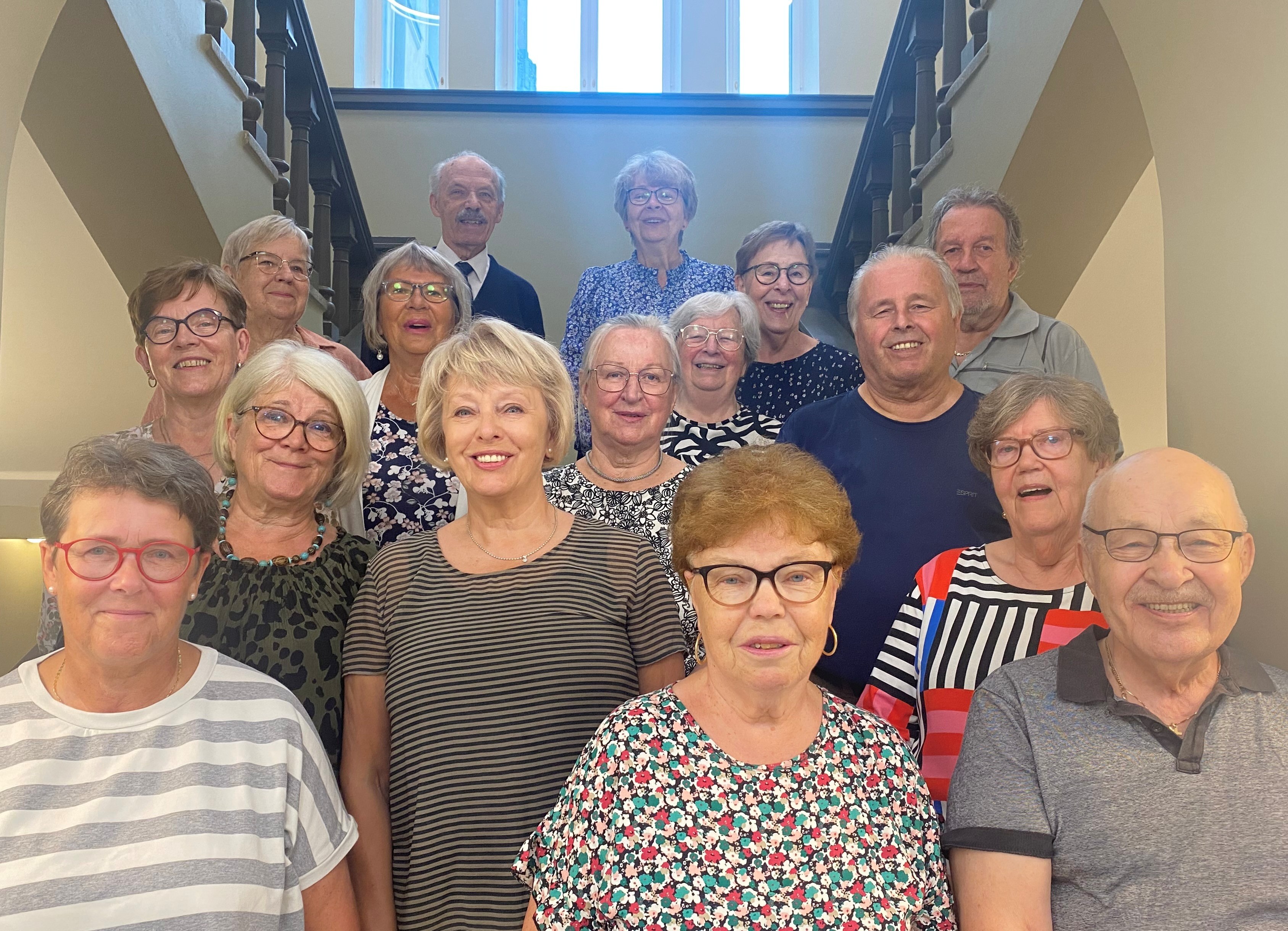 Senior Citizens' Council standing indoors in front of a staircase, all smiling.