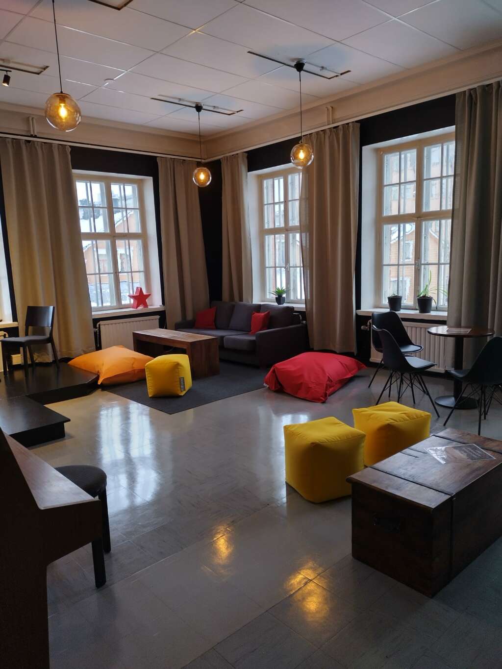 Café Kultsa, jossa on suuri sohva, värikkäitä säkkituoleja, puupöytiä ja suuria ikkunoita, joista tulvii luonnonvaloa.