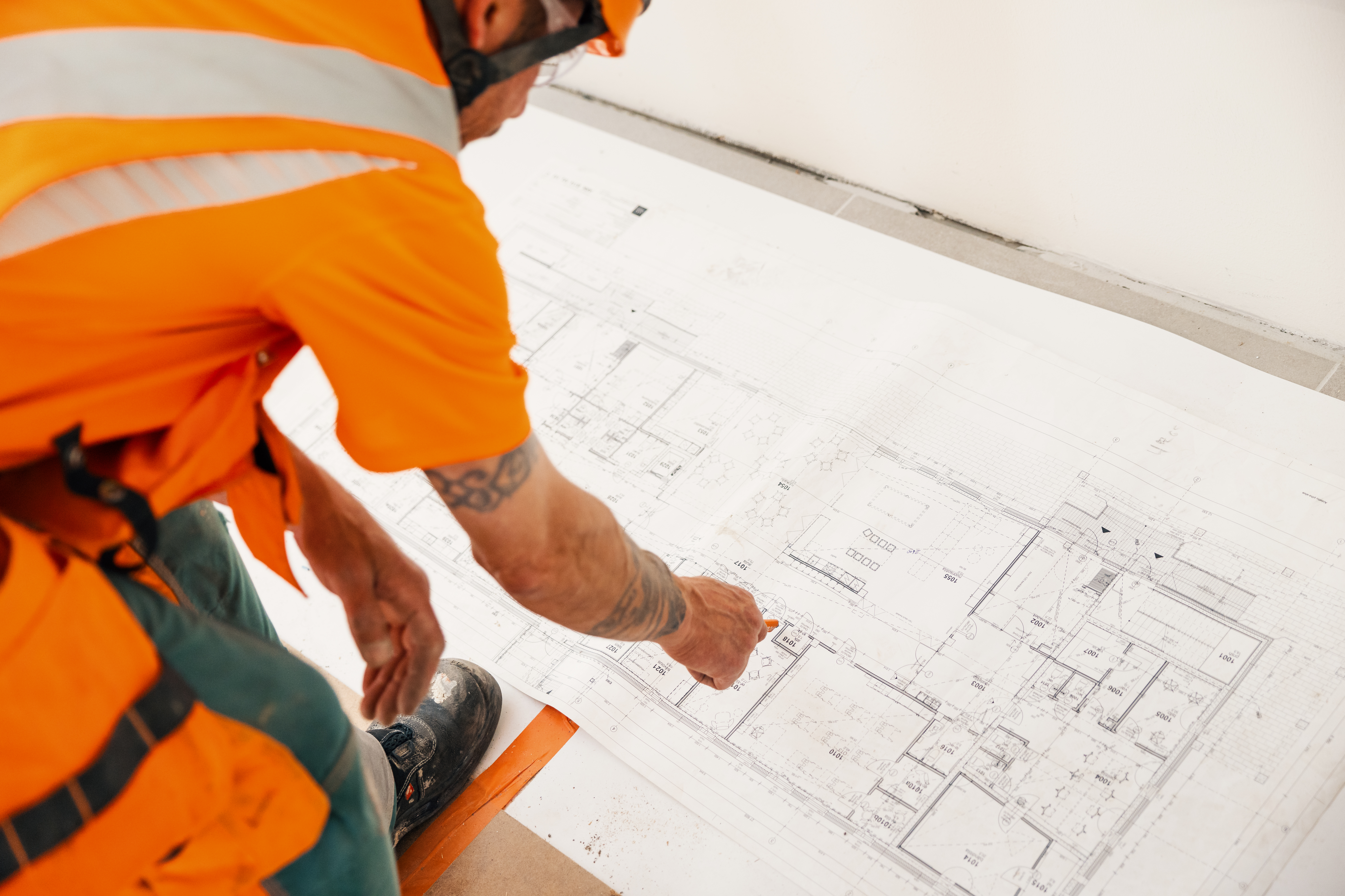 Construction worker examining building plans on the floor.