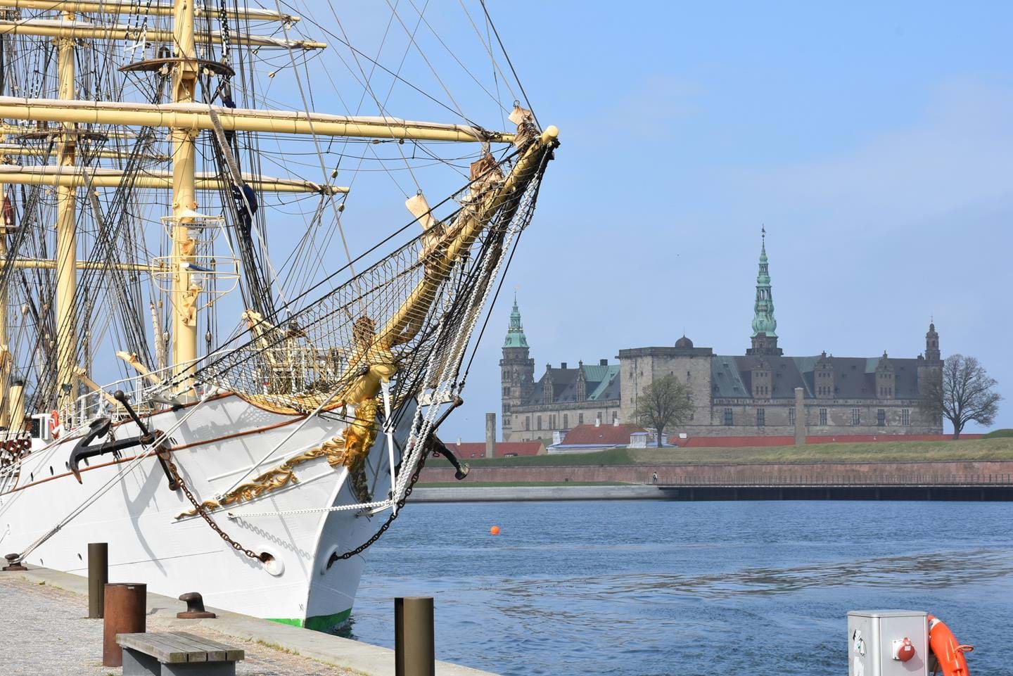 Old sail boat that has a castle in the background.