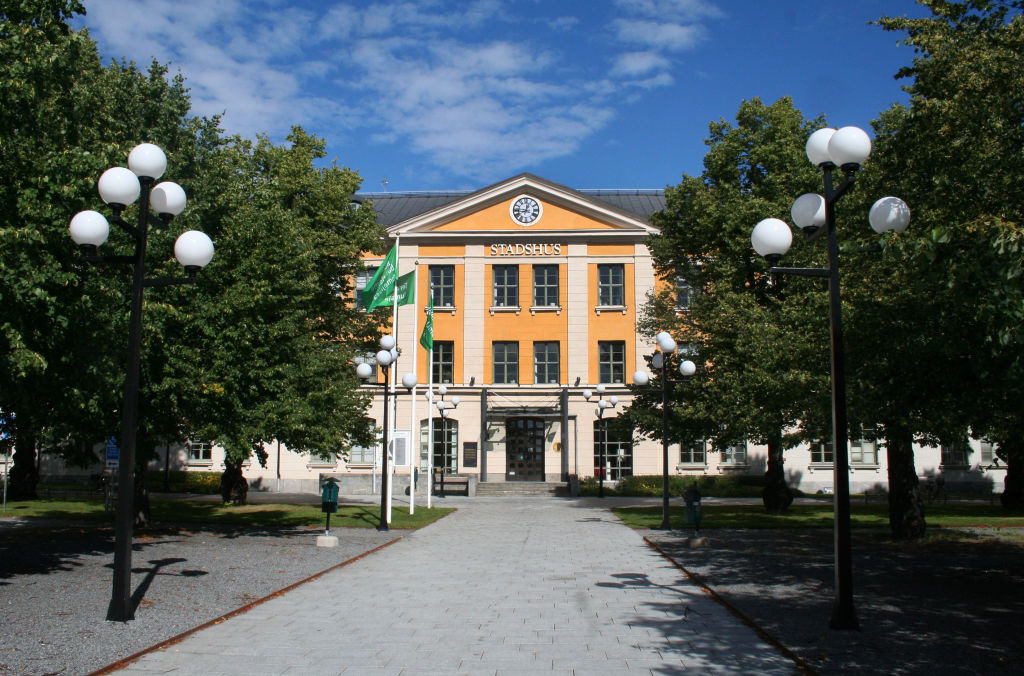 A yeallow city hall building at the end of a boulevard.
