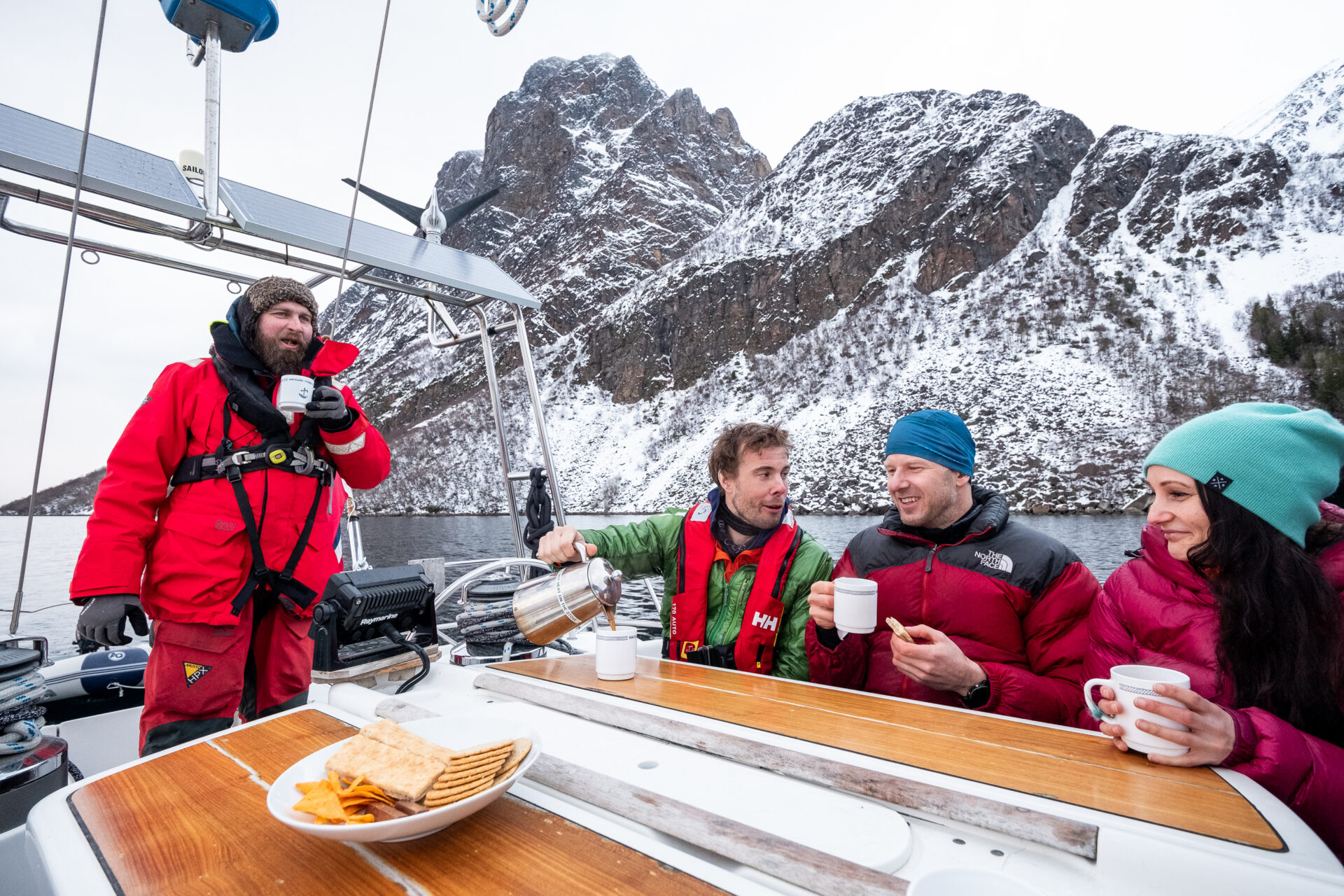 People drink coffee on a boat. There are mountains in the background.