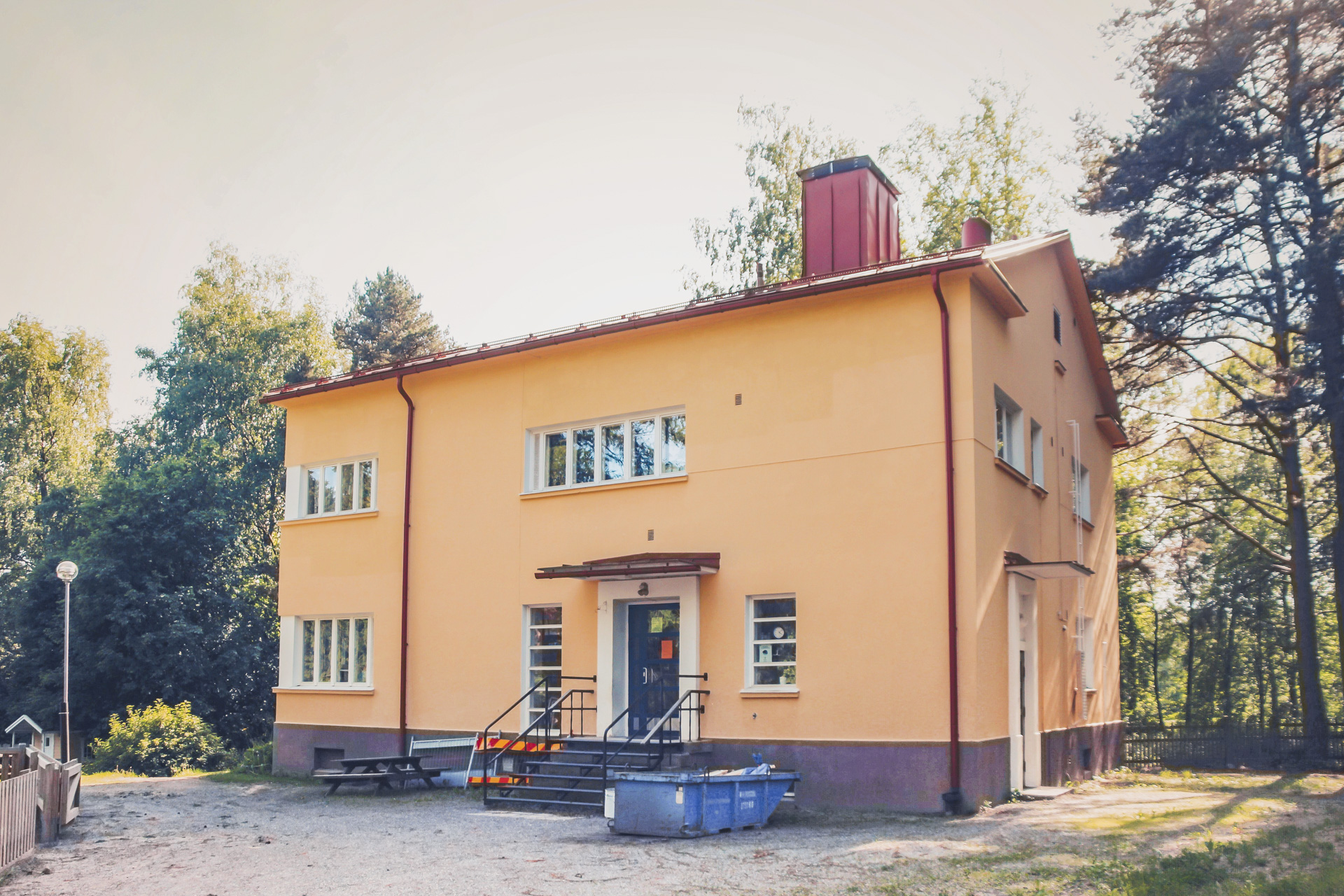 Ett tvåvånings gult hus beläget i en grön miljö.